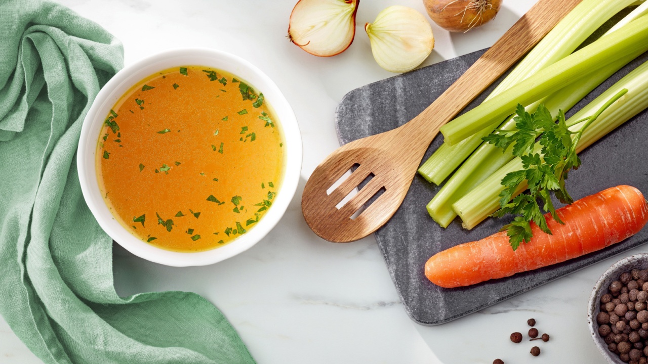 bowl of fresh chicken broth on kitchen table, top view