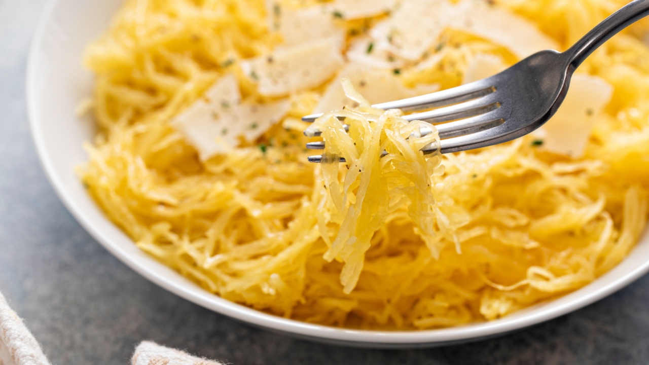 Spaghetti squash roasted and pulled apart served with olive oil and parmesan, low carb recipe idea, with a fork swirled in