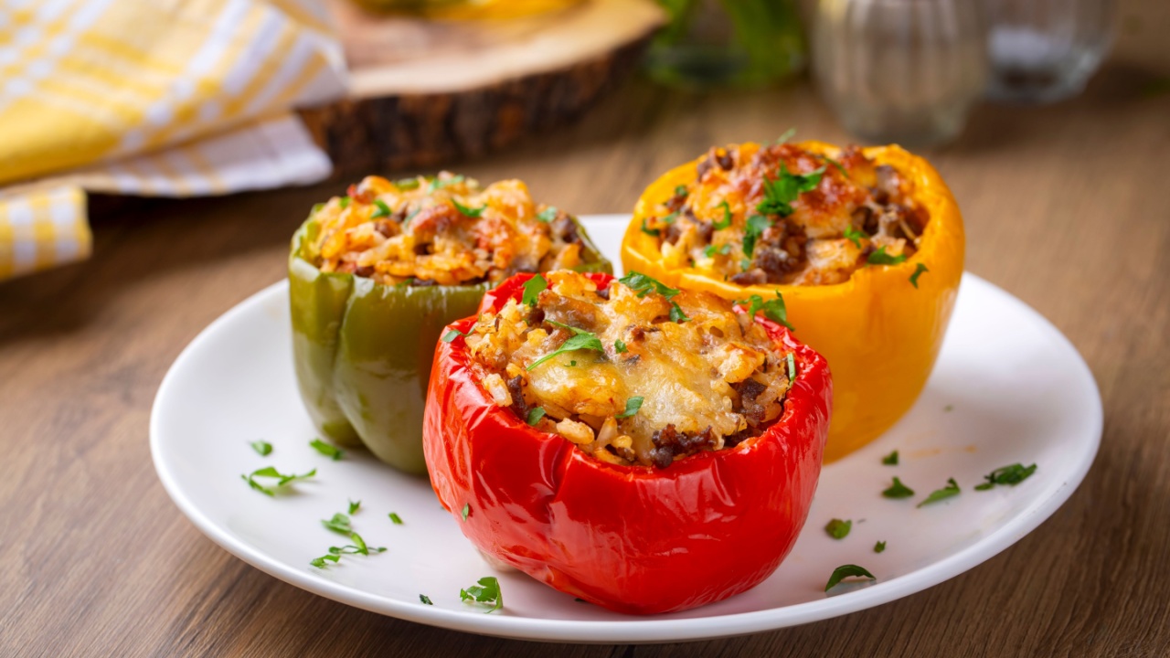 Stuffed peppers, halves of peppers stuffed with rice, dried tomatoes, herbs and cheese in a baking dish on a blue wooden table, top view