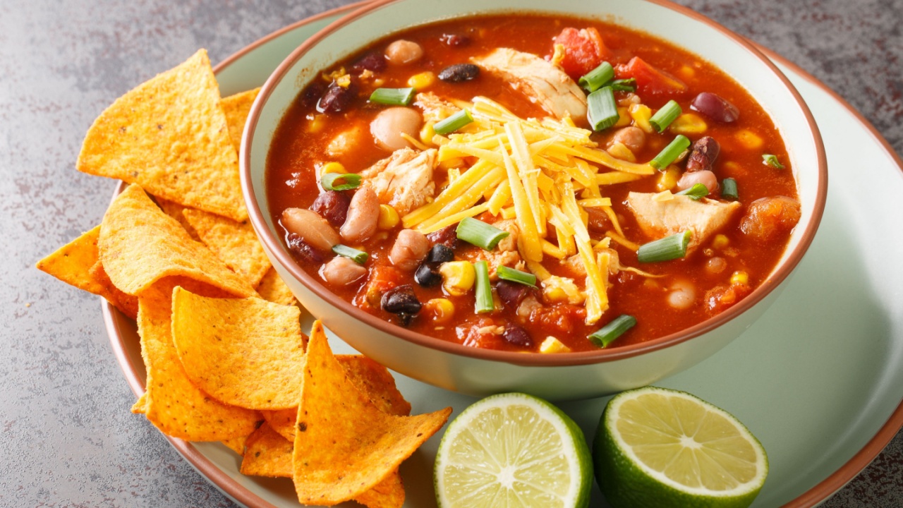 Tasty chicken taco soup full of tender chicken, sweet corn, black beans, fire-roasted tomatoes, and the most delicious creamy broth close-up in a plate on the table. Horizontal
