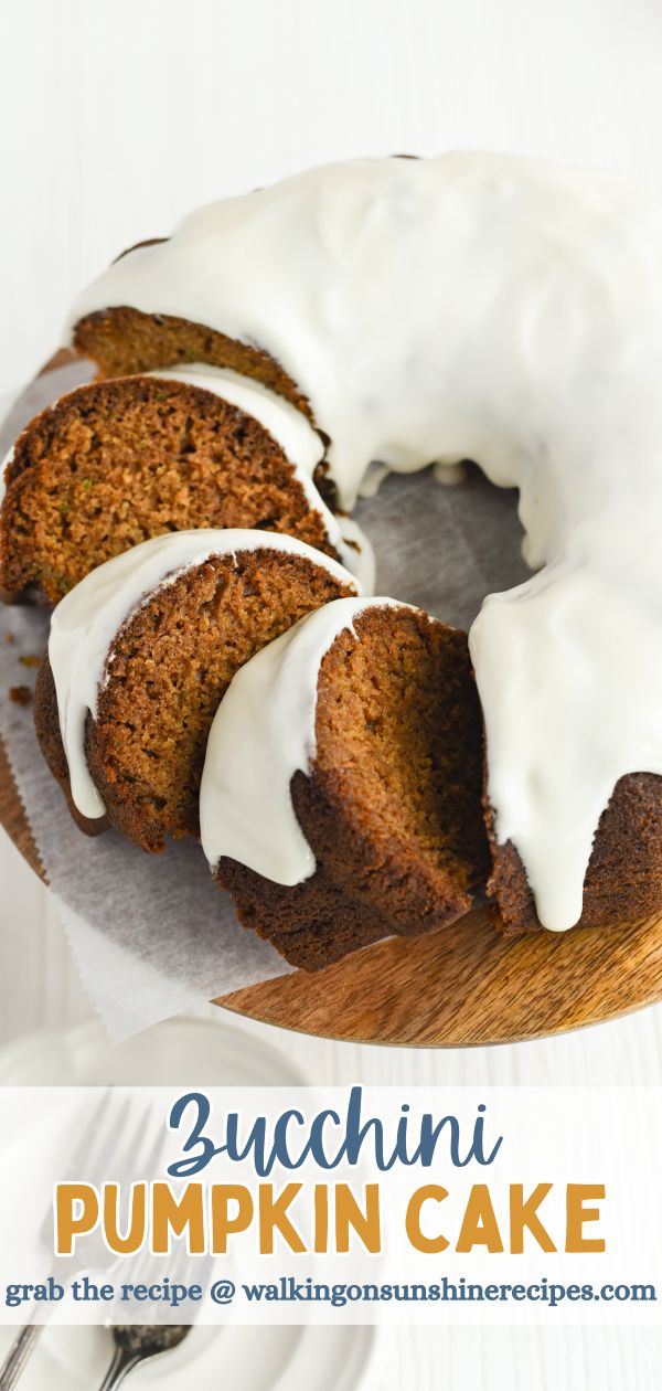 Zucchini Pumpkin bundt cake sliced on wooden plate with cream cheese frosting.