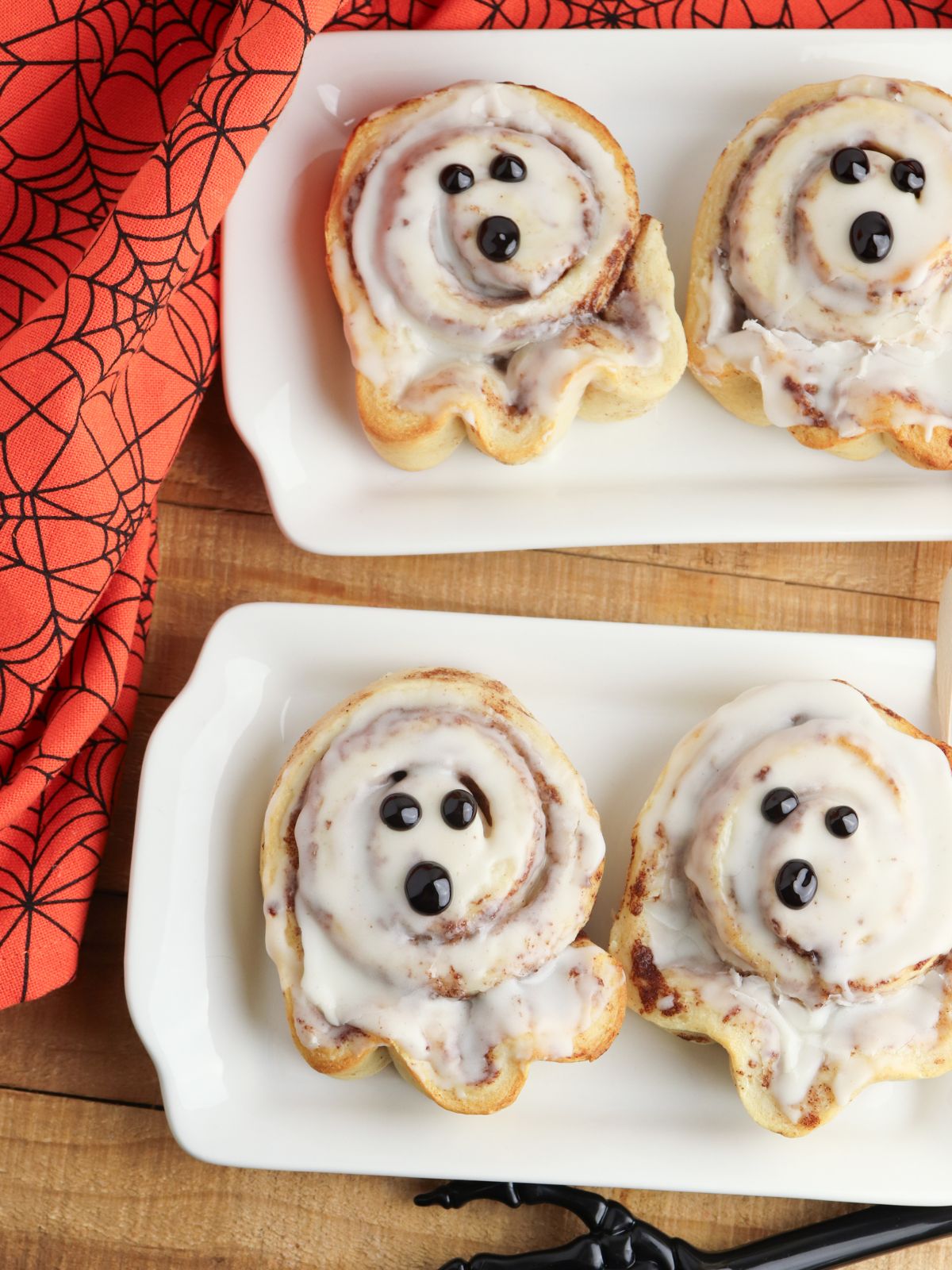 Two rectangle platters both with 2 ghost cinnamon rolls.