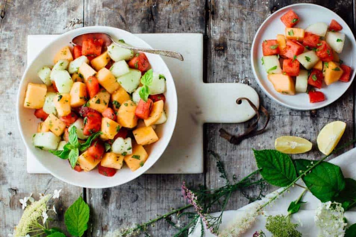 two bowls of melon salad with fresh herbs and mint.