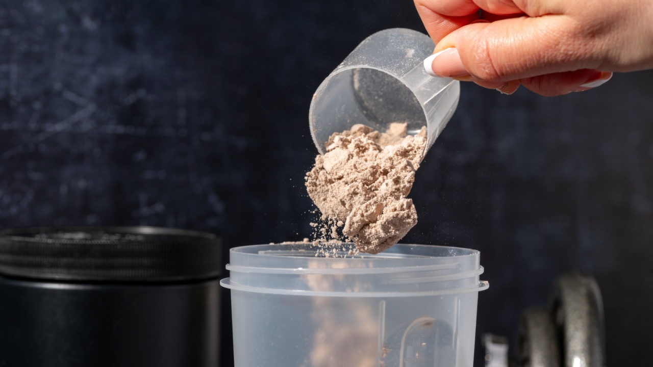 pouring chocolate protein powder in a shaker. Food supplements. Dark background. Bodybuilding, fitness, gym.