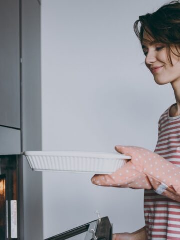 woman puts casserole in oven