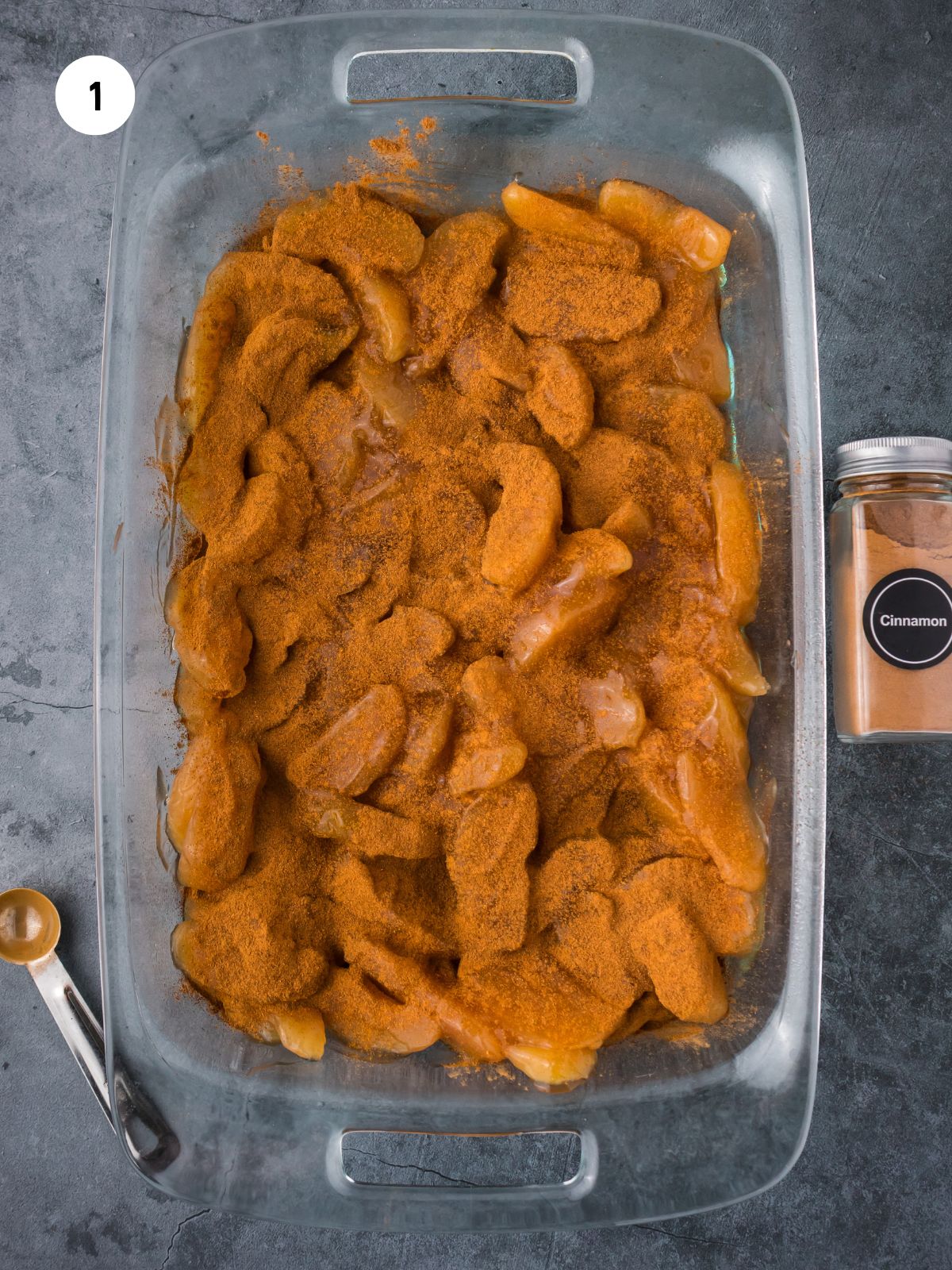 Apple filling and cinnamon in the bottom of a clear 9x13 baking dish.