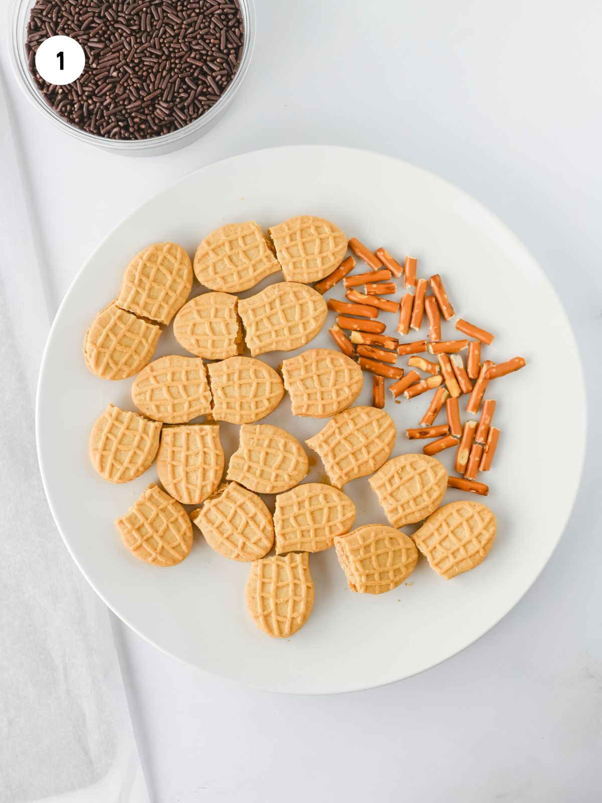 Nutter Butter cookies cut in half and pretzel sticks cut in half on a plate.