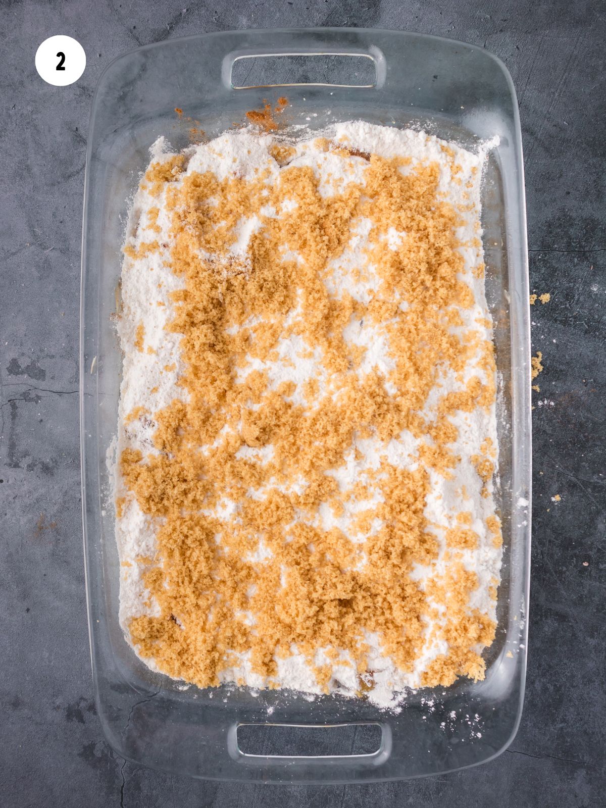 Cake mix and brown sugar on top of the apples in the baking dish.