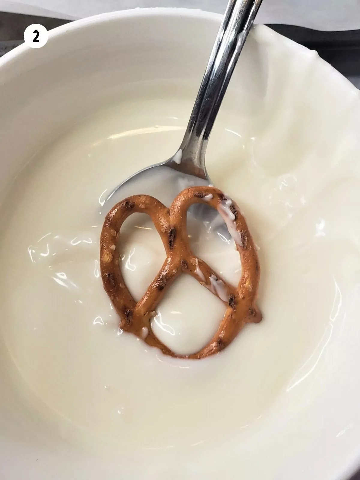 Dipping pretzel in melted white chocolate.