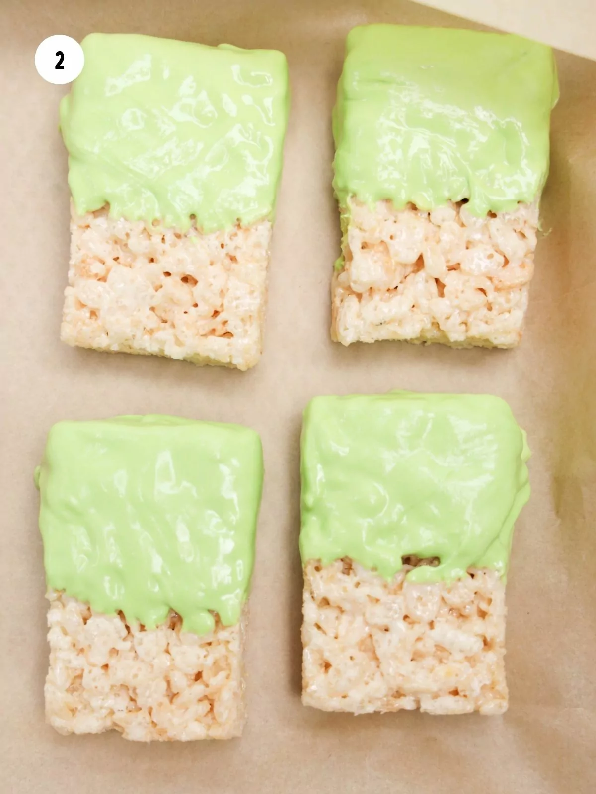 Four rice krispie treats dipped in lime green chocolate.