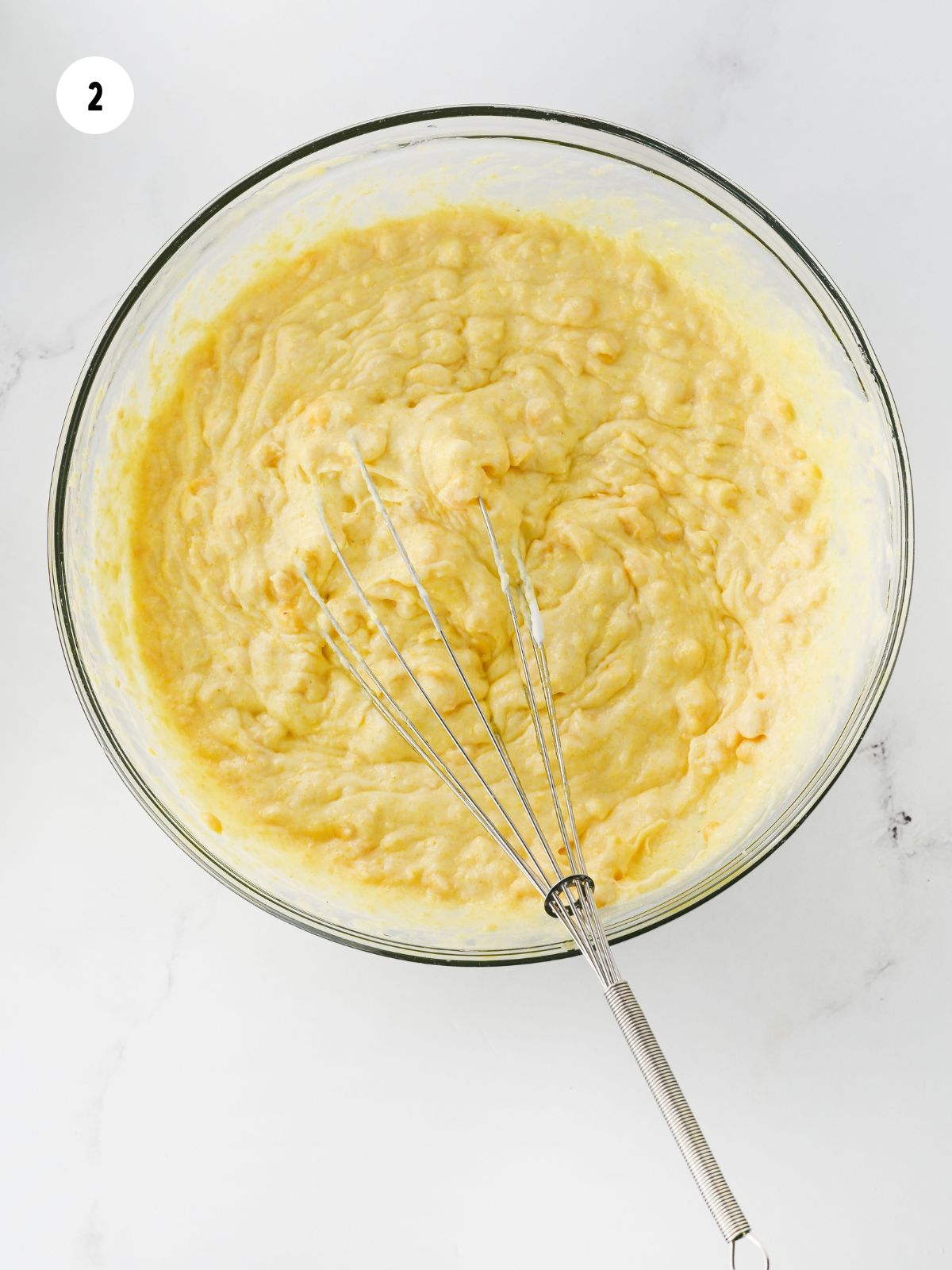 Corn casserole batter in a clear mixing bowl.