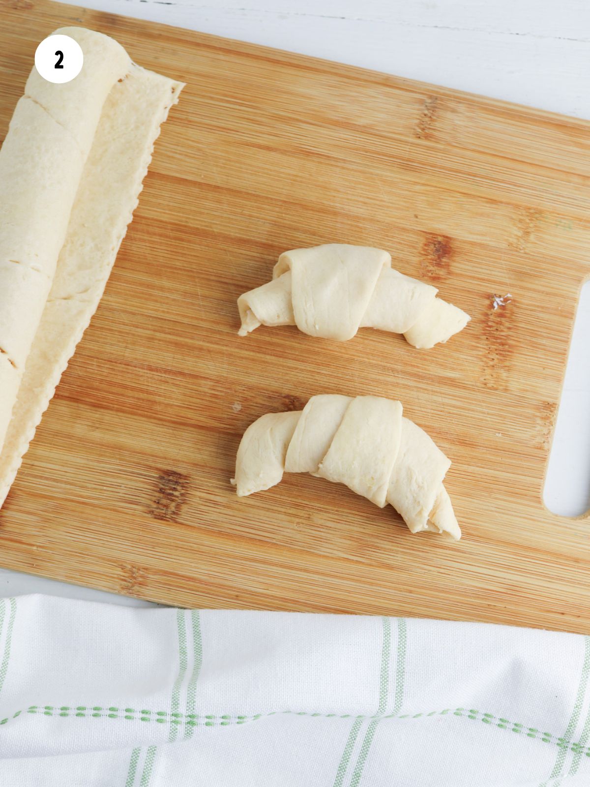 rolled up crescent rolls on a wood cutting board.