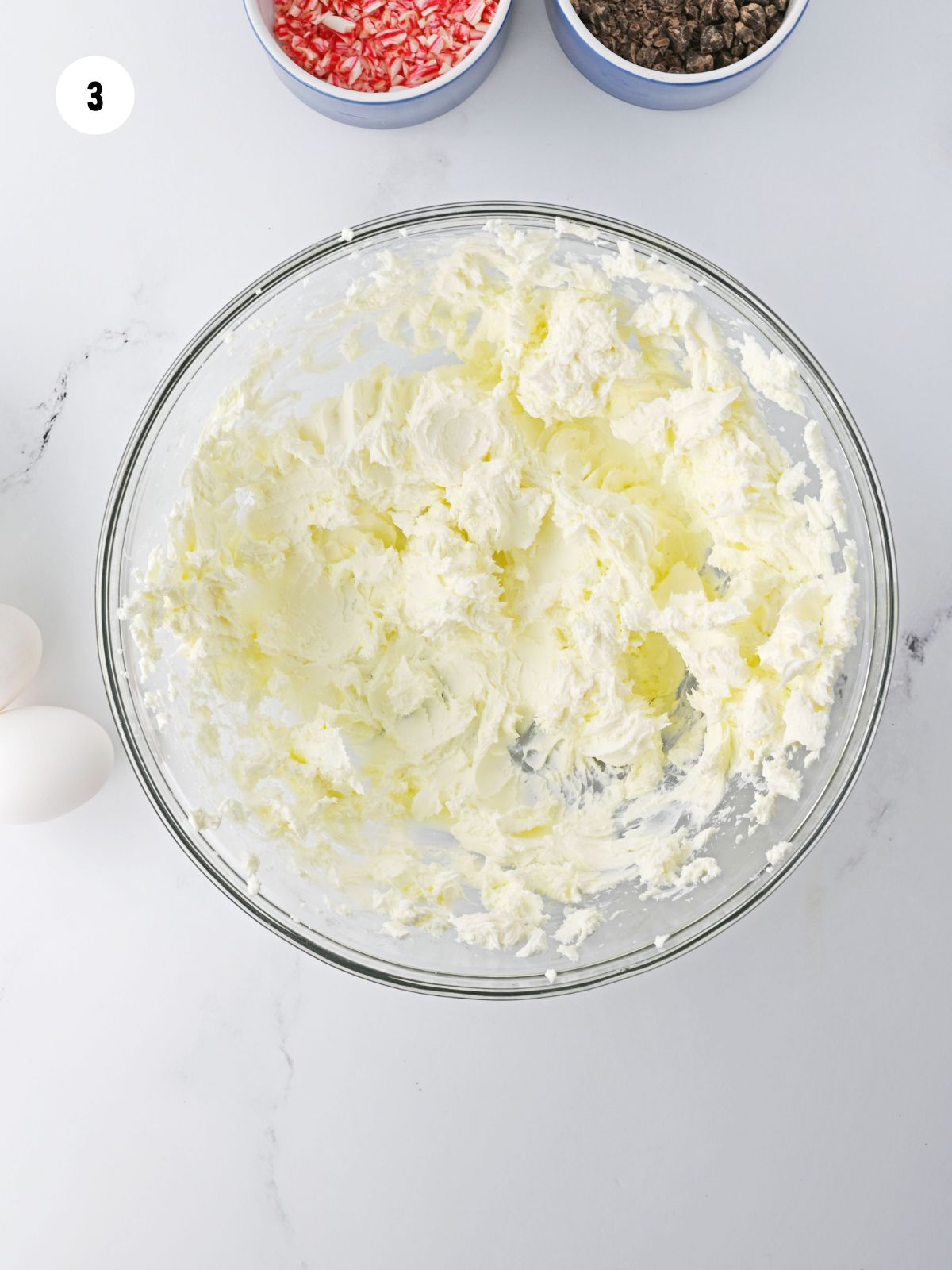 Clear mixing bowl filled with beaten cream cheese.