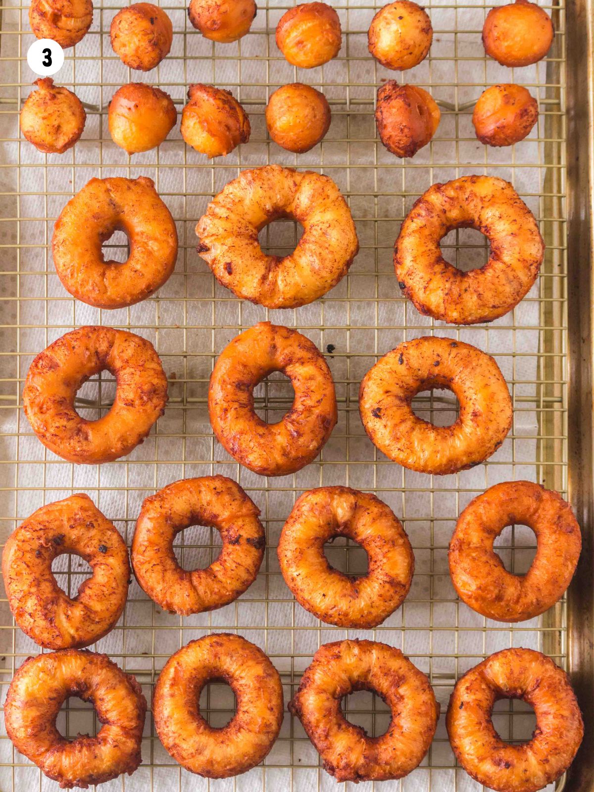 drain fried cinnamon roll donuts on a wire rack.
