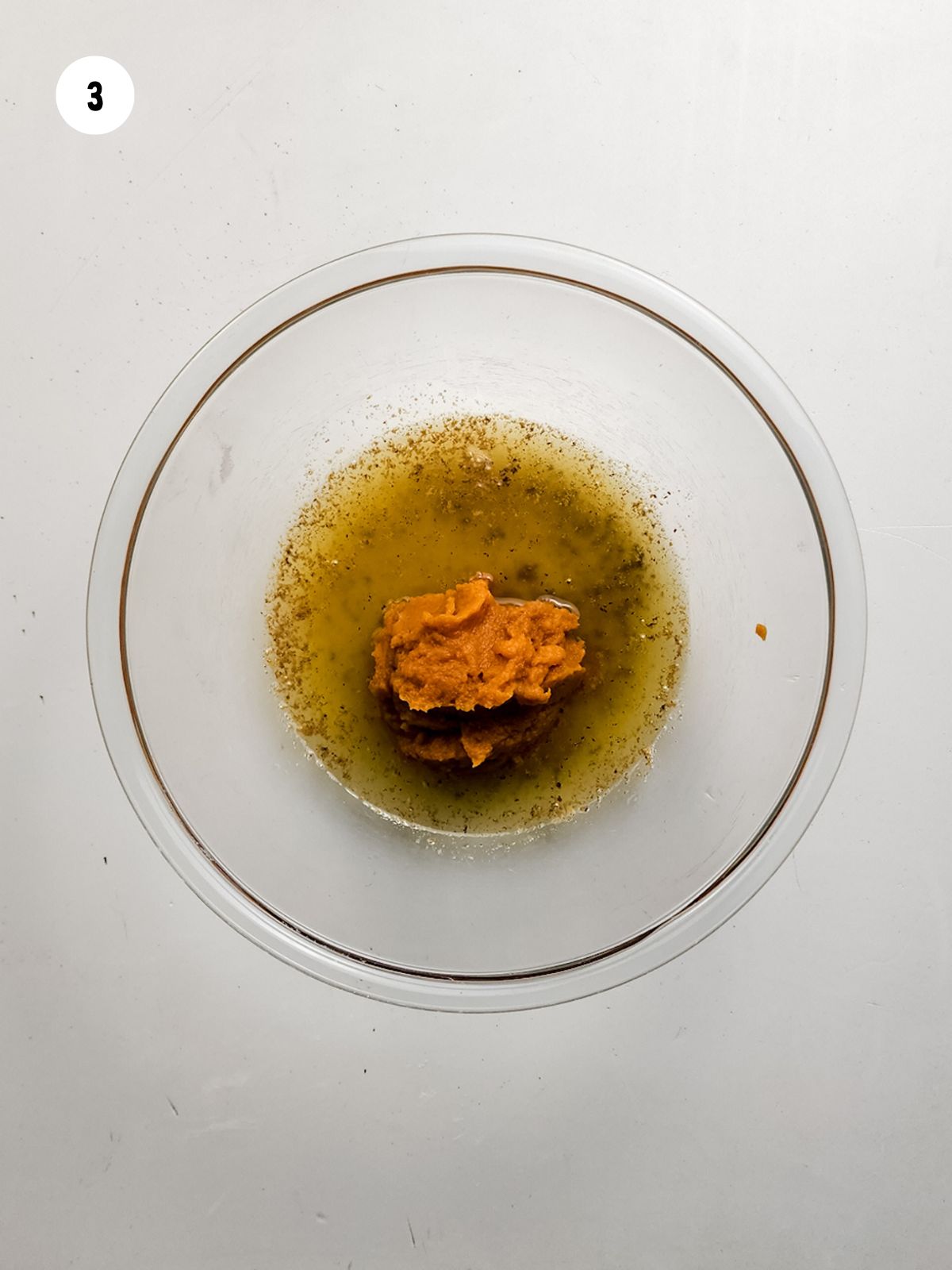 Melted butter and pumpkin puree in a clear mixing bowl.