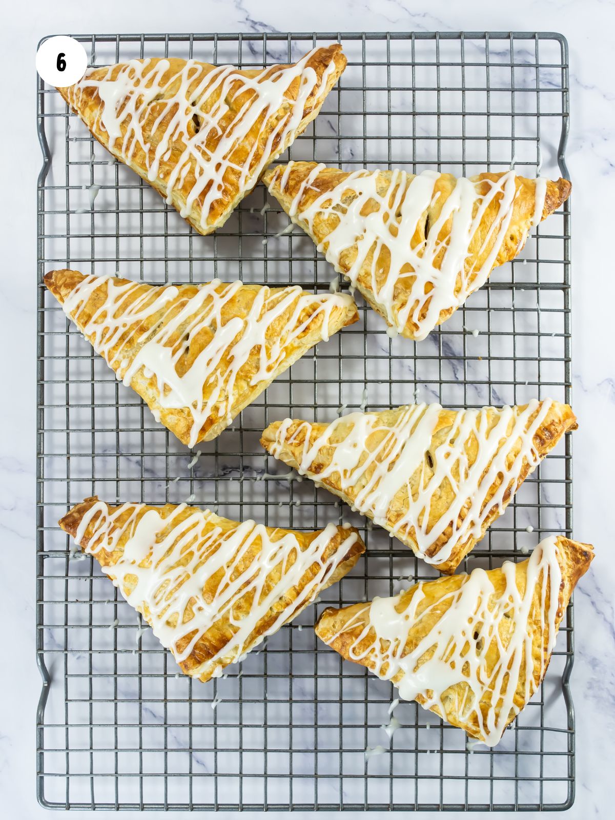 Glaze drizzled on top of the turnovers cooling on the wire rack.