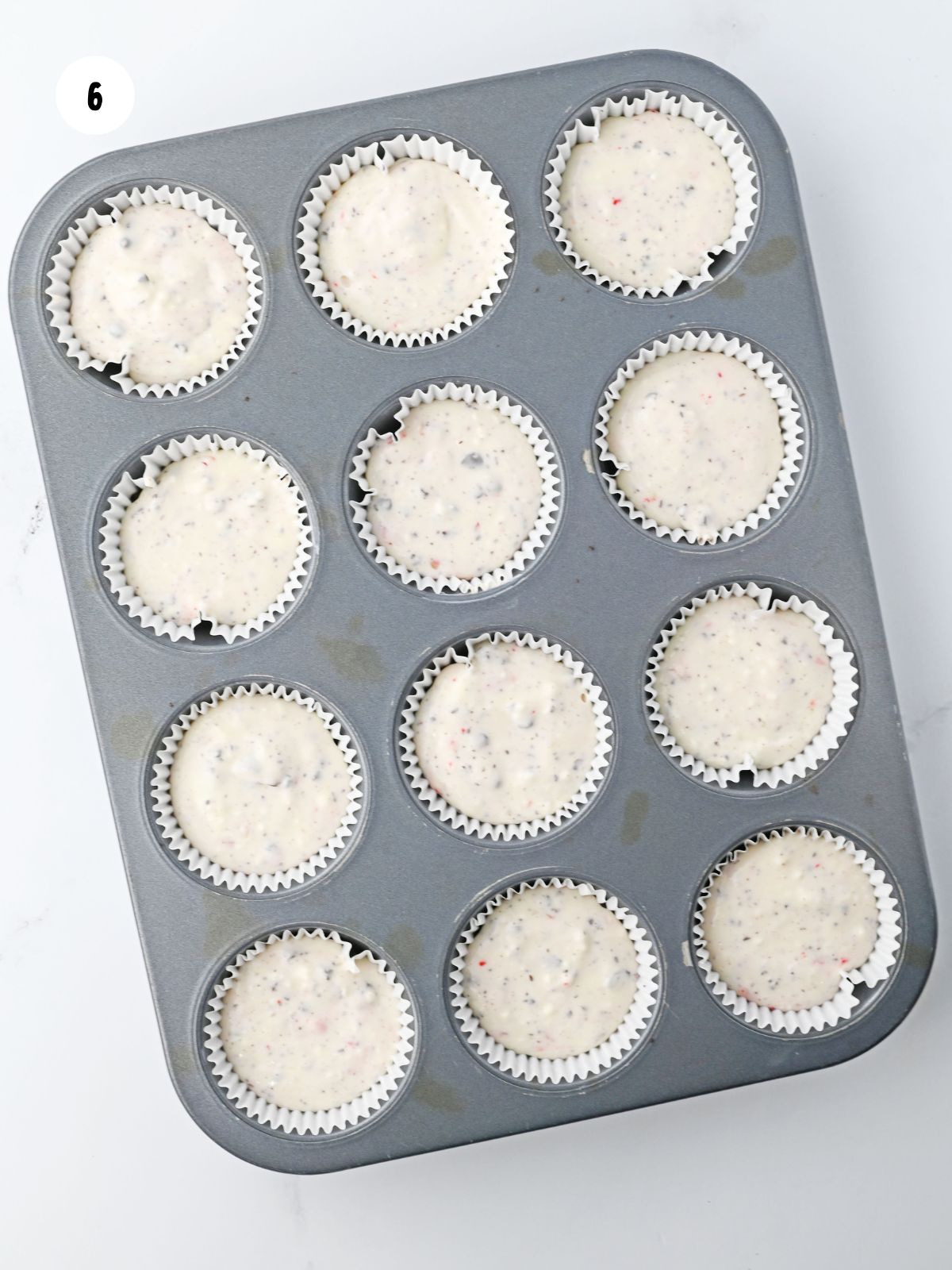 Cheesecake filling added on top of the crusts in the muffin tin.