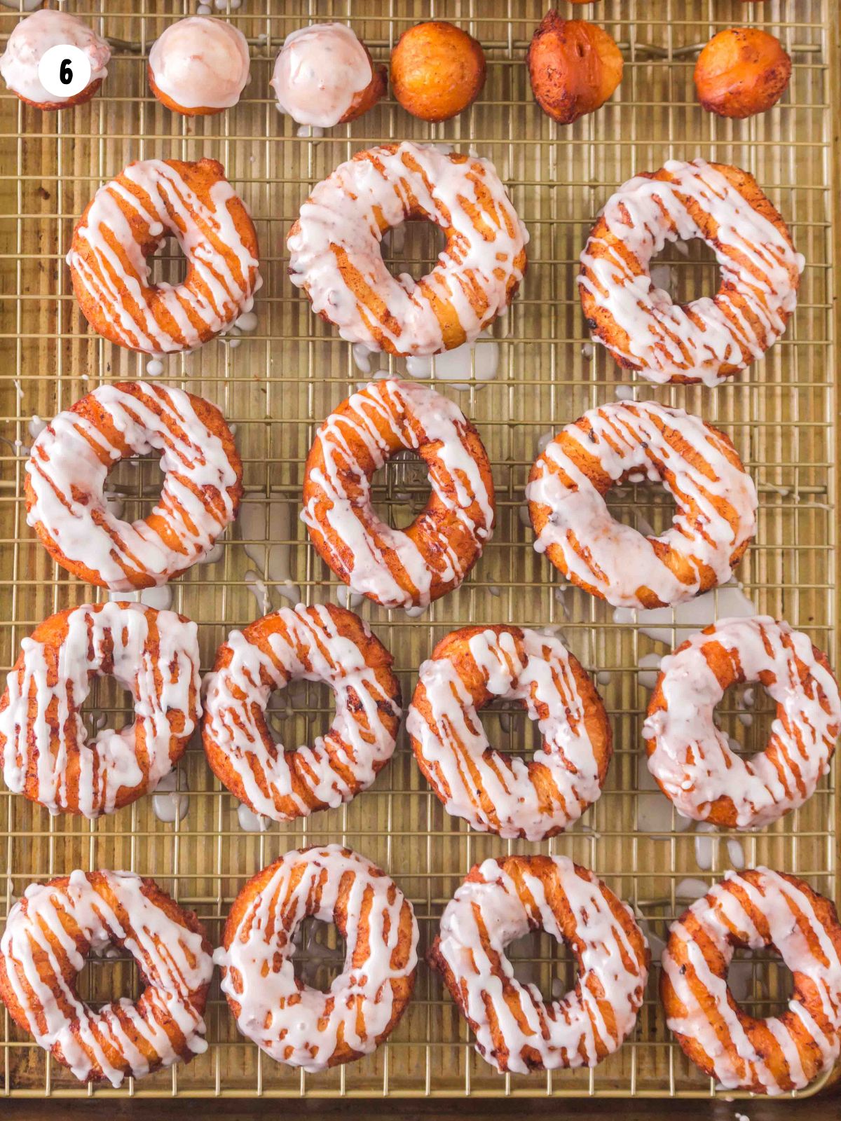 Wire rack full of cinnamon roll donuts and donut holes with glaze.