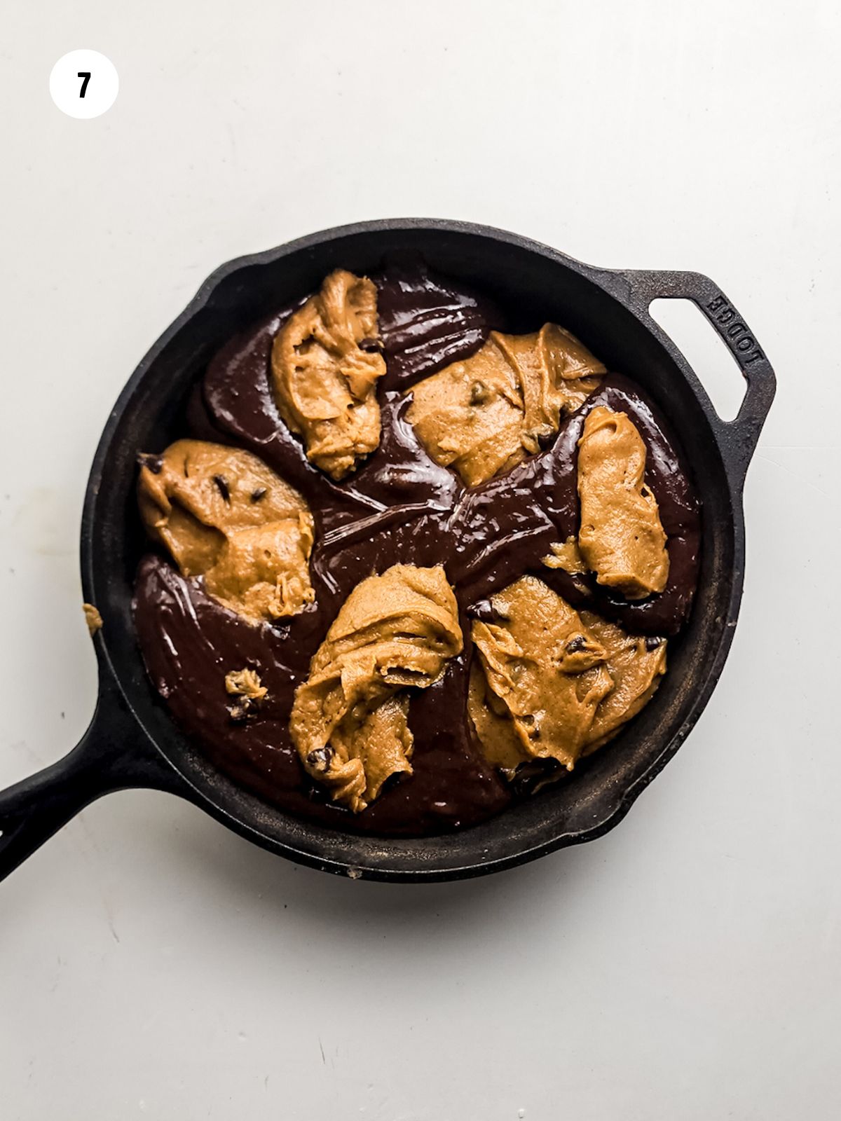 Dollops of brownie batter and cookie dough in a skillet.
