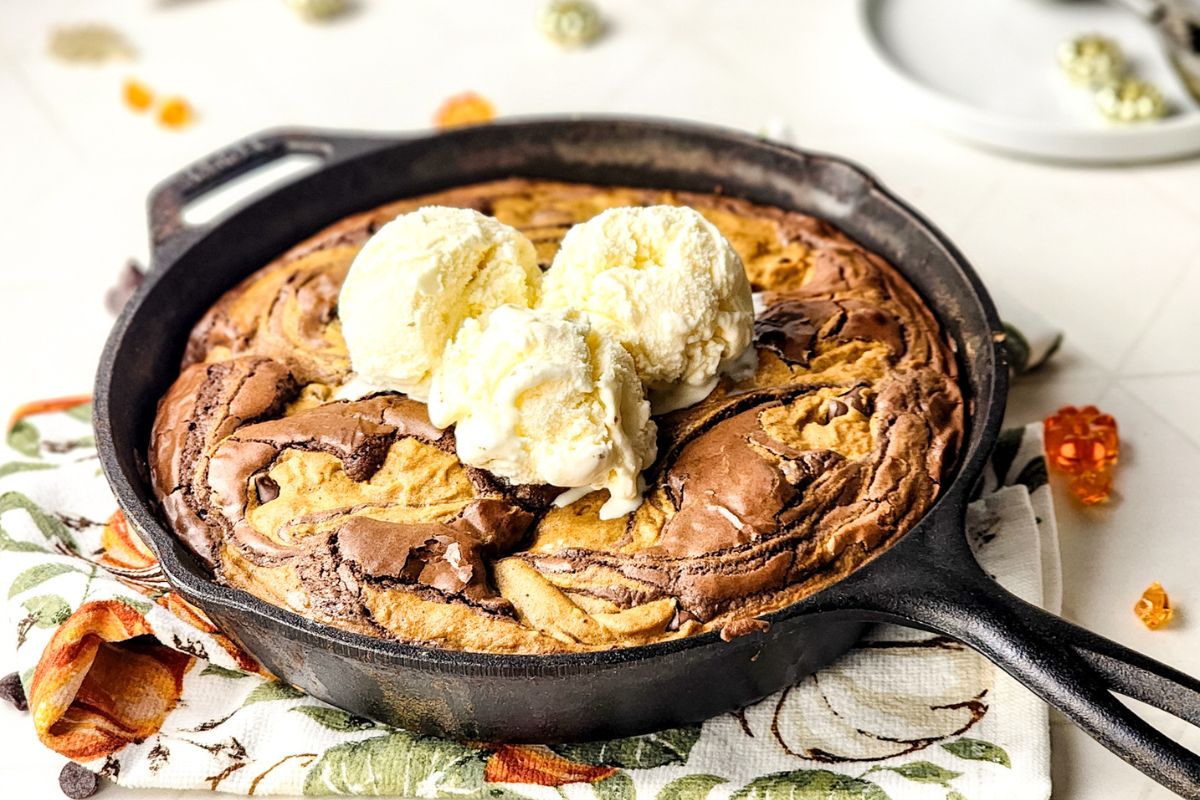Iron skillet with pumpkin brookies topped with vanilla ice cream.