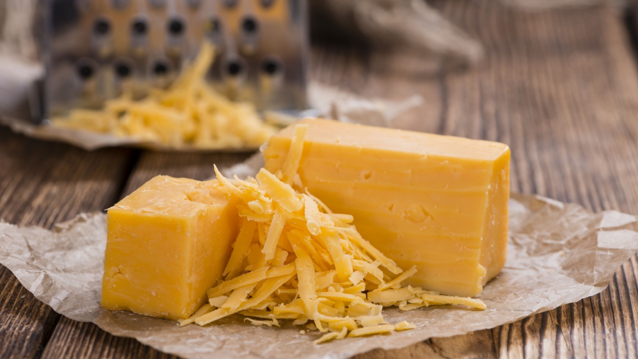 Cheddar Cheese (grated) as close-up shot on an old vintage wooden table