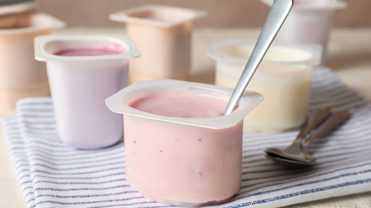 Composition with plastic cups with yogurt on white table