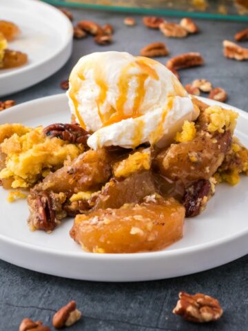 Apple Dump Cake served with a scoop of vanilla ice cream and a drizzle of caramel.