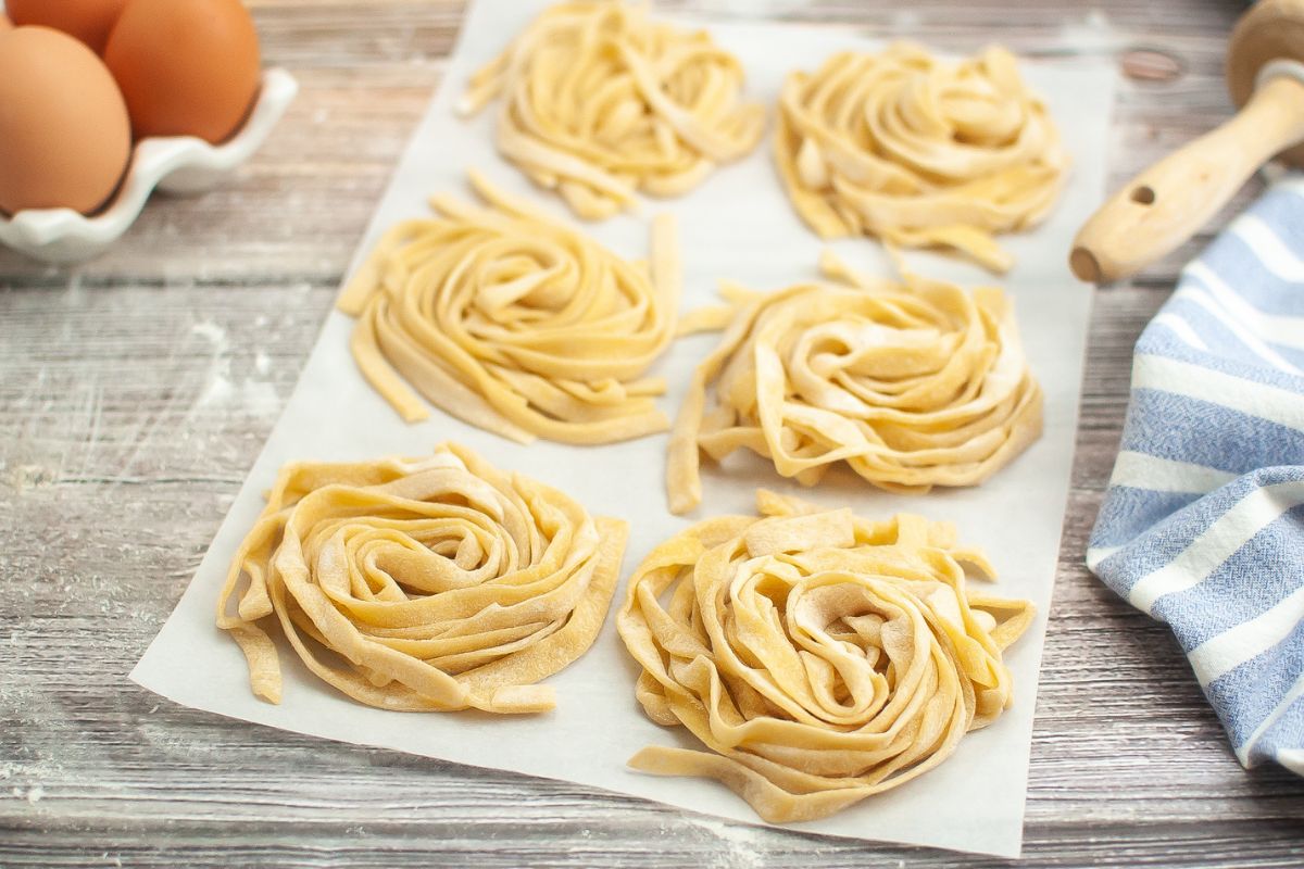 6 mounds of homemade pasta on parchment paper.