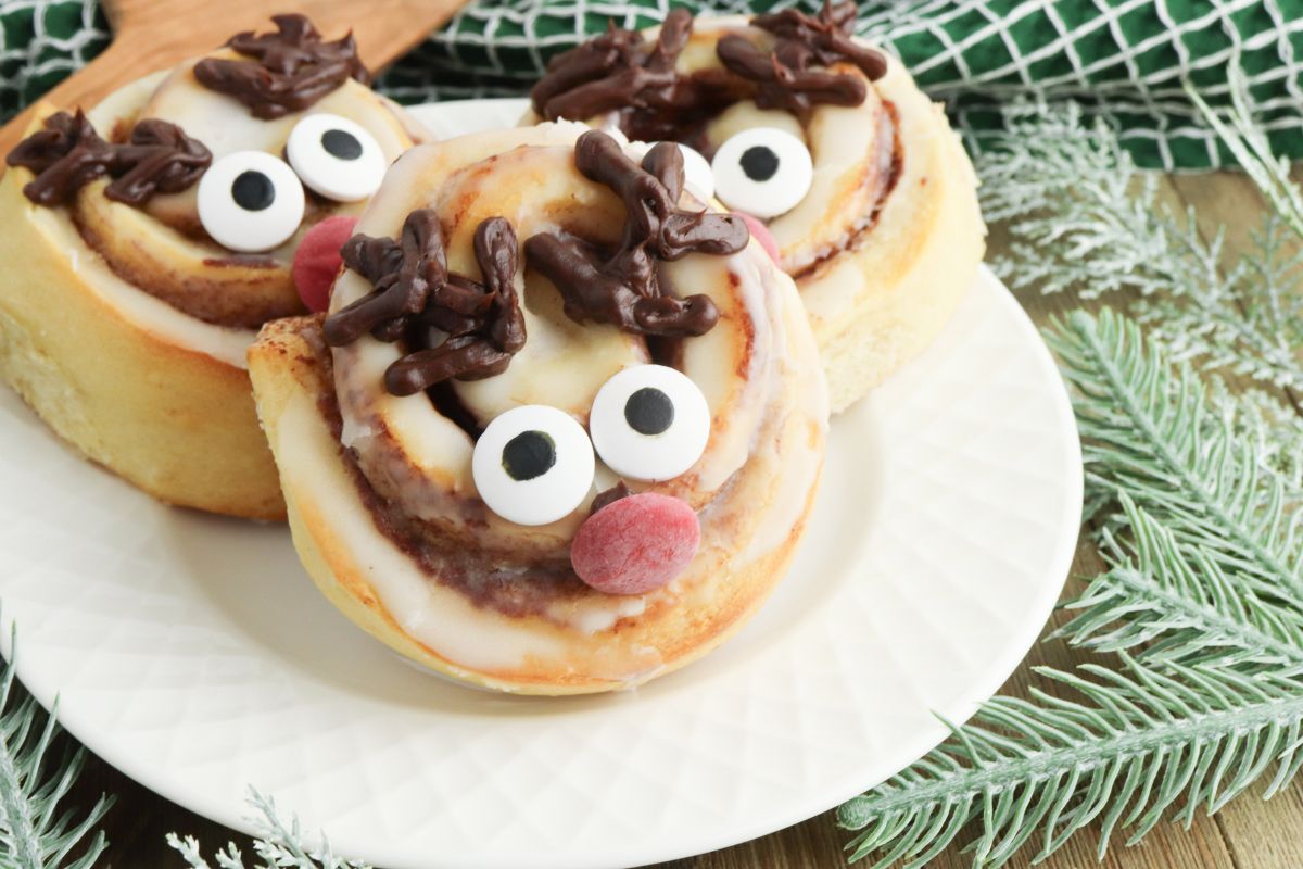 Plate of 3 cinnamon rolls decorated like Rudolph the Red Nose Reindeer.