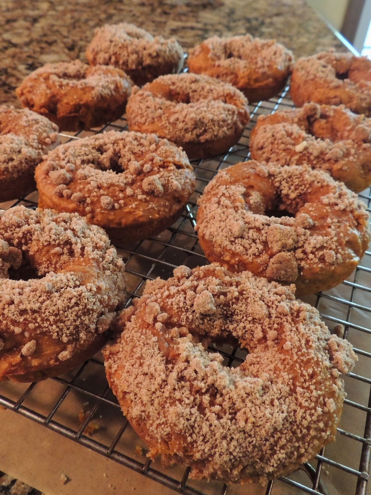 pumpkin donuts baked on cooling rack with crumb topping.