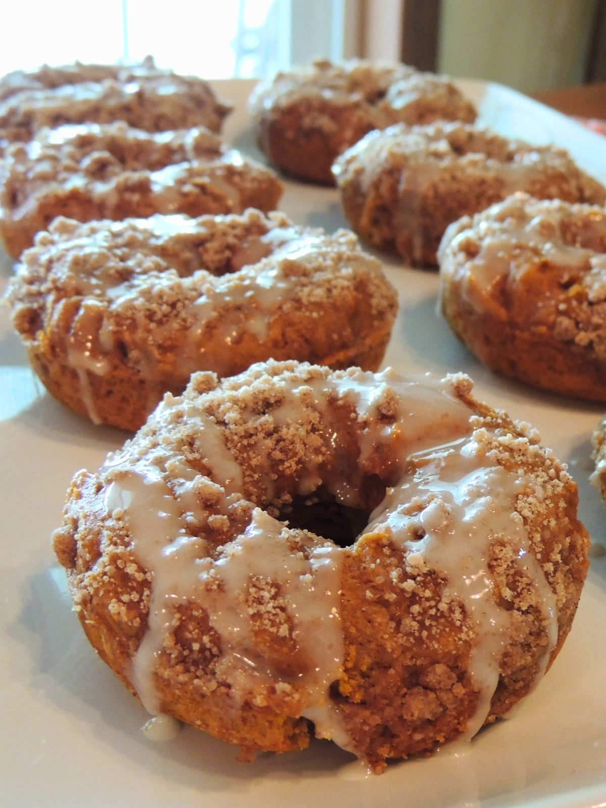 glazed pumpkin crumb donuts closeup on white platter.
