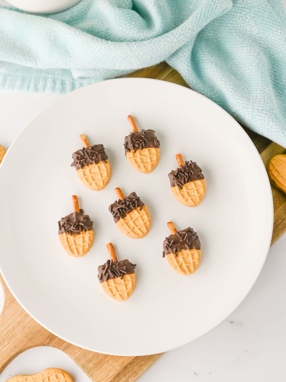 white plate filled with cookies that are decorated like acorns.