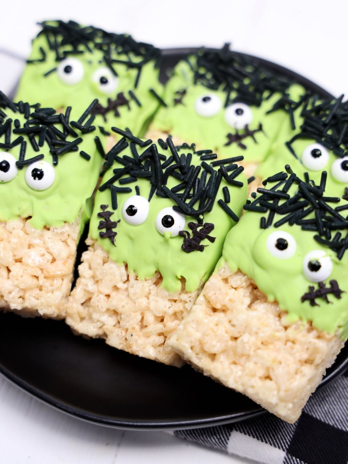 Six Frankenstein Rice Krispie Treats on a black plate.