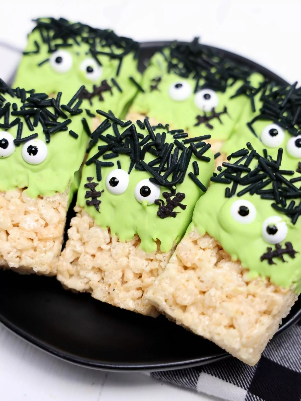 Six Frankenstein Rice Krispie Treats on a black plate.