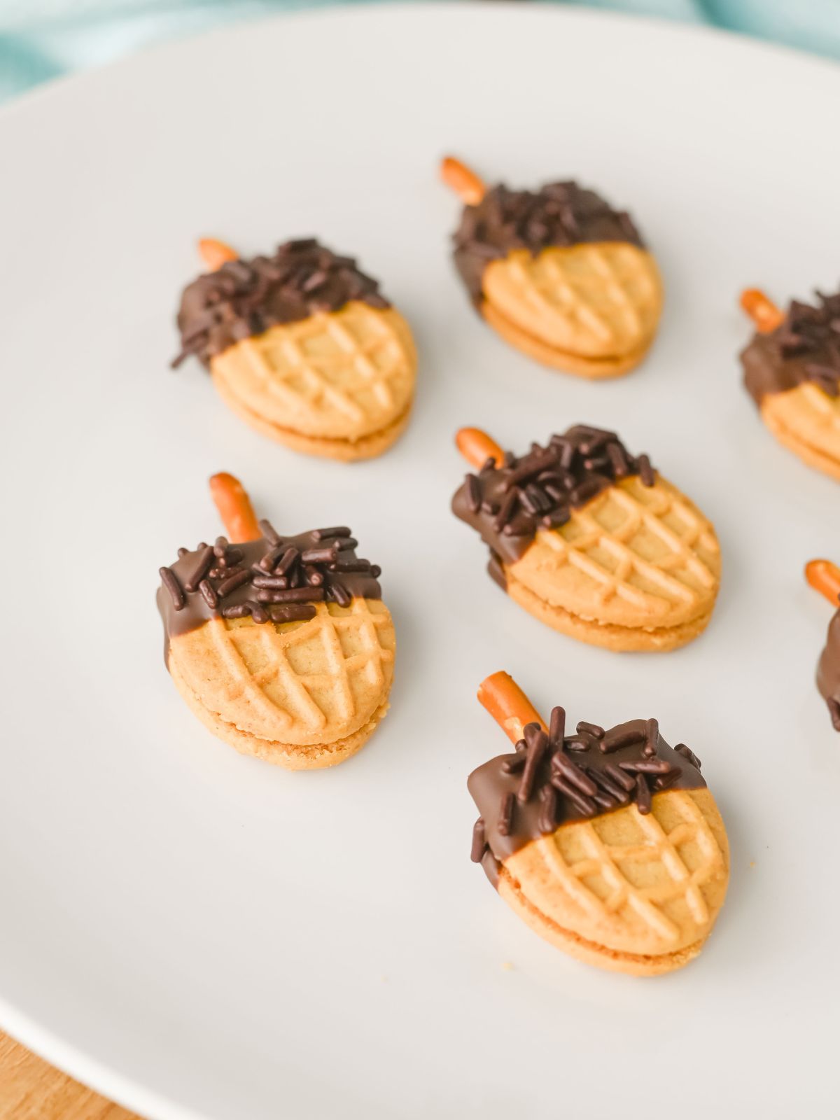 Close up of the peanut butter chocolate dipped cookies decorated like acorns.