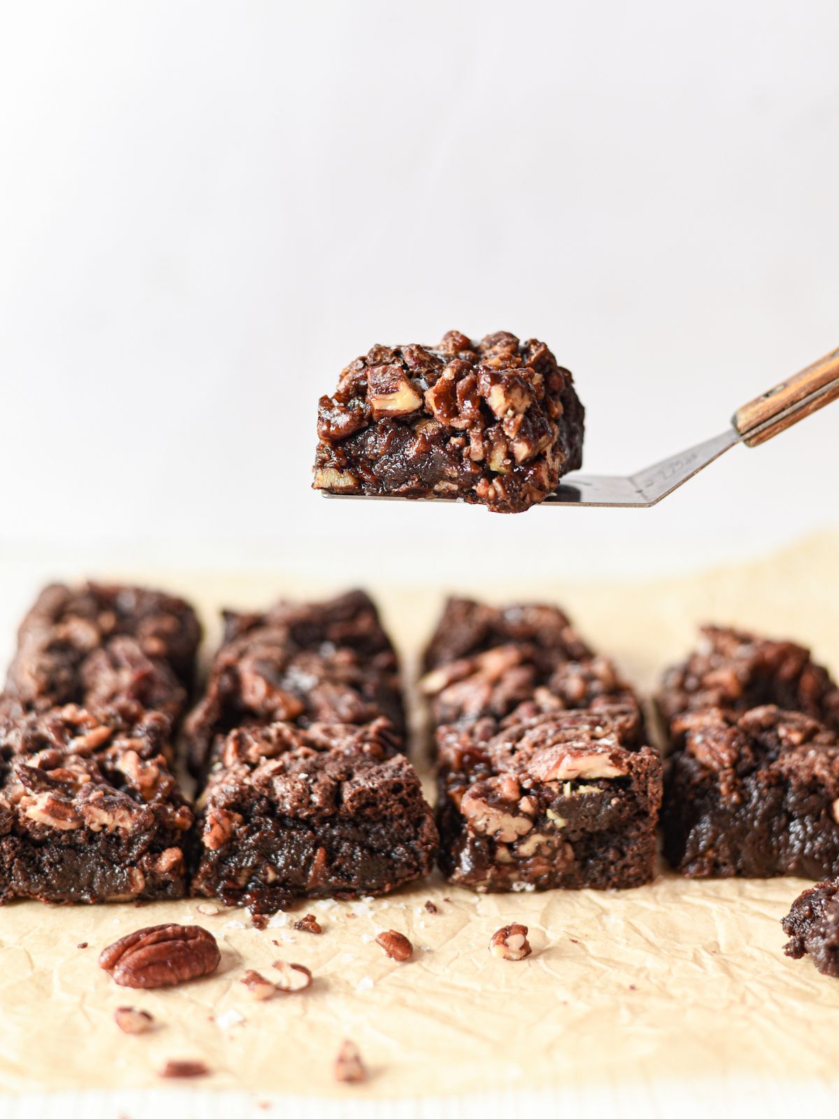Pecan pie brownie being lifted up on a serving spatula from the rest of the brownies.