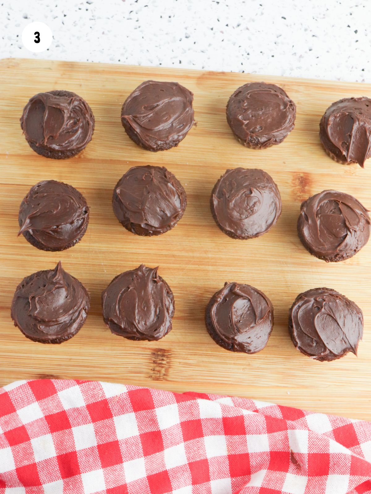 chocolate cupcakes with chocolate frosting on a wood board.