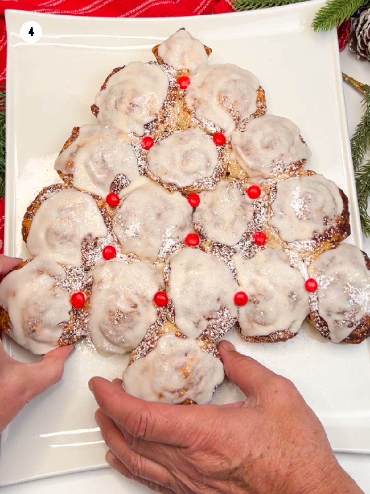 Hands reaching for the pull apart cinnamon rolls.