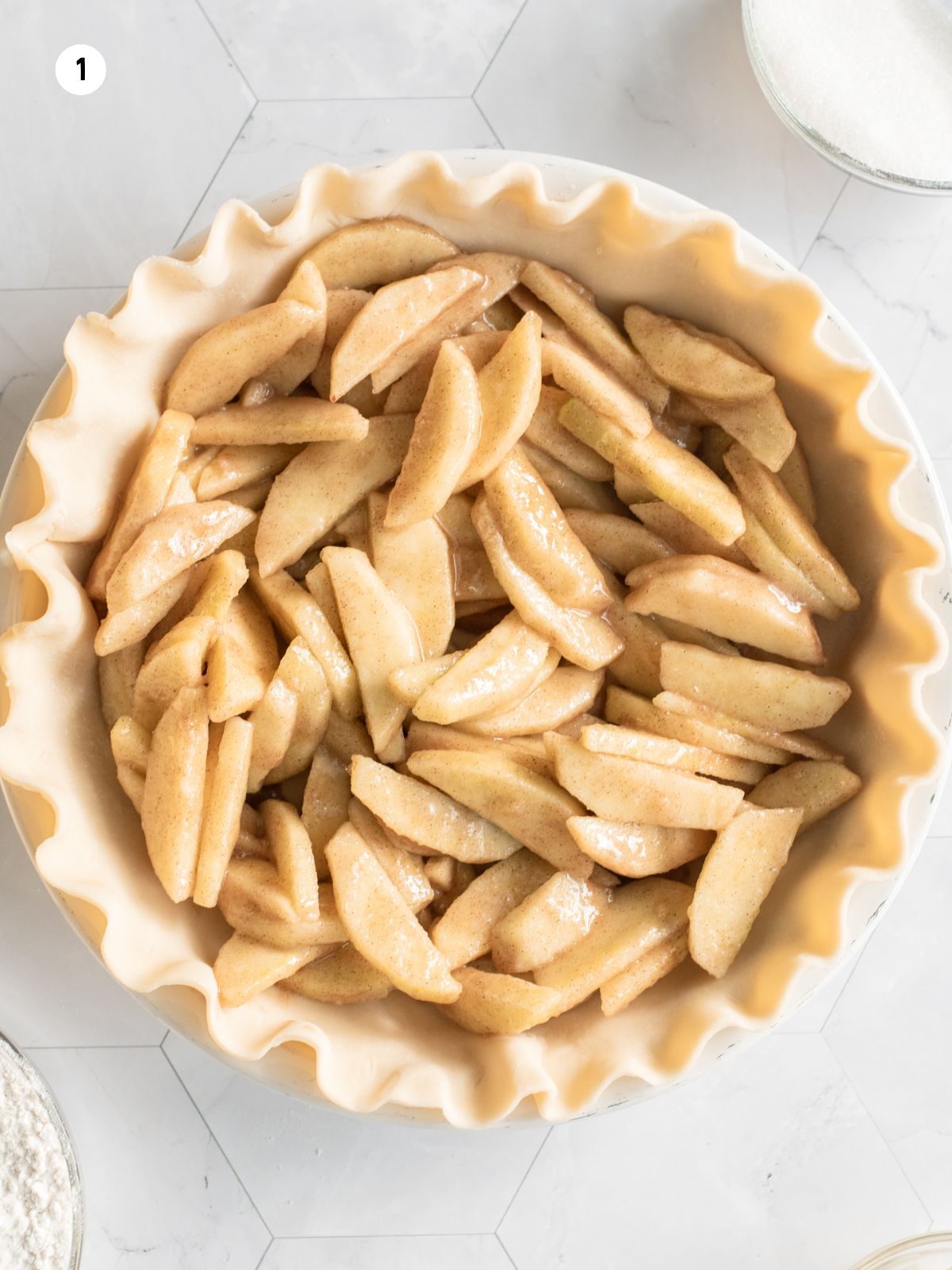sliced apples in homemade pie crust dough in pie plate.