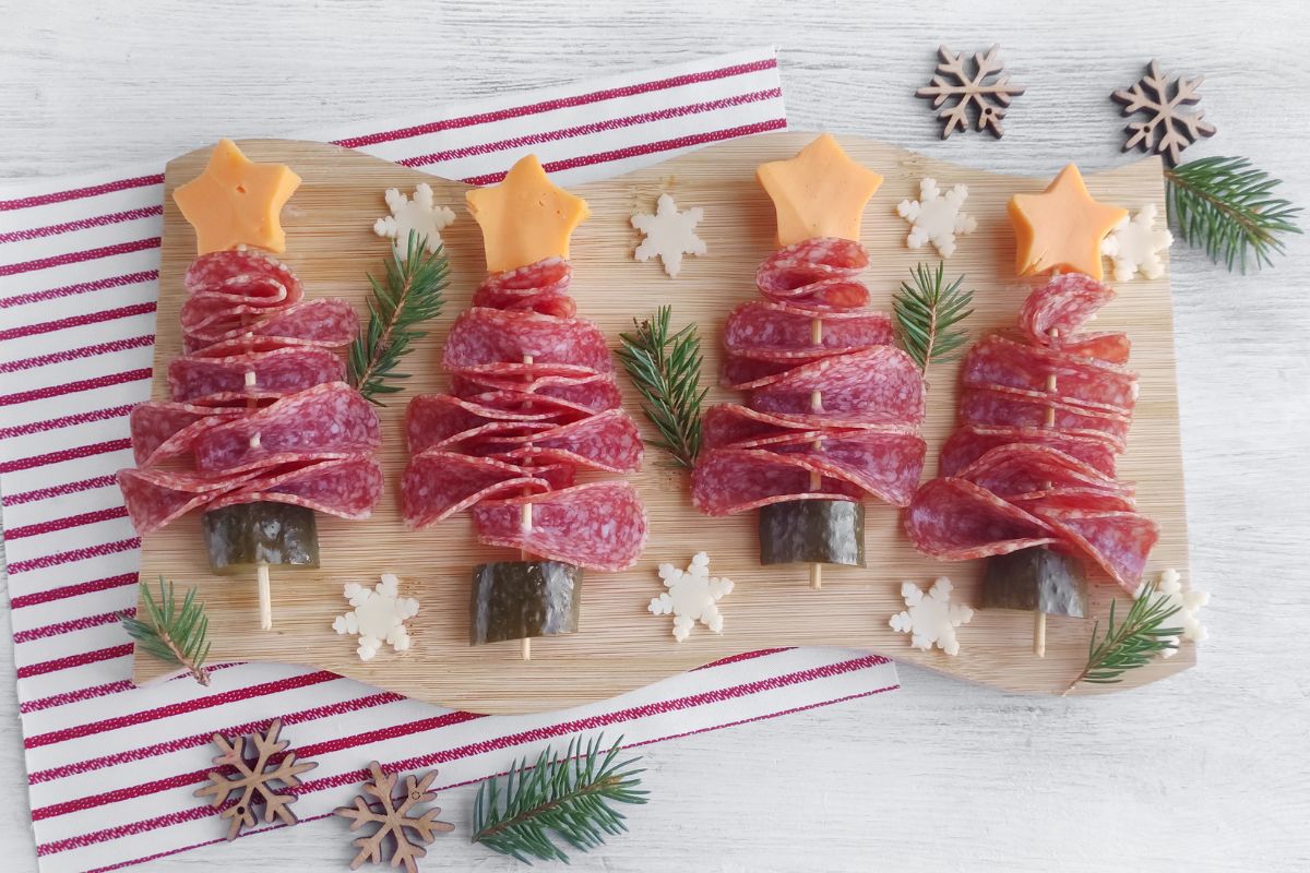 Four Christmas Tree Salami Appetizers on a wavy wood board.
