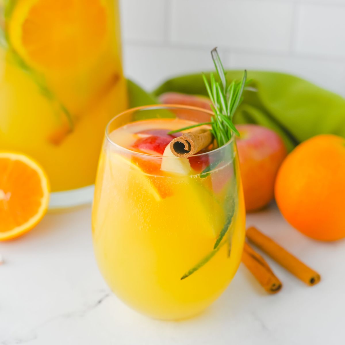 closeup of a sparkling cider drink with fall flavors or apples, oranges and cinnamon sticks.