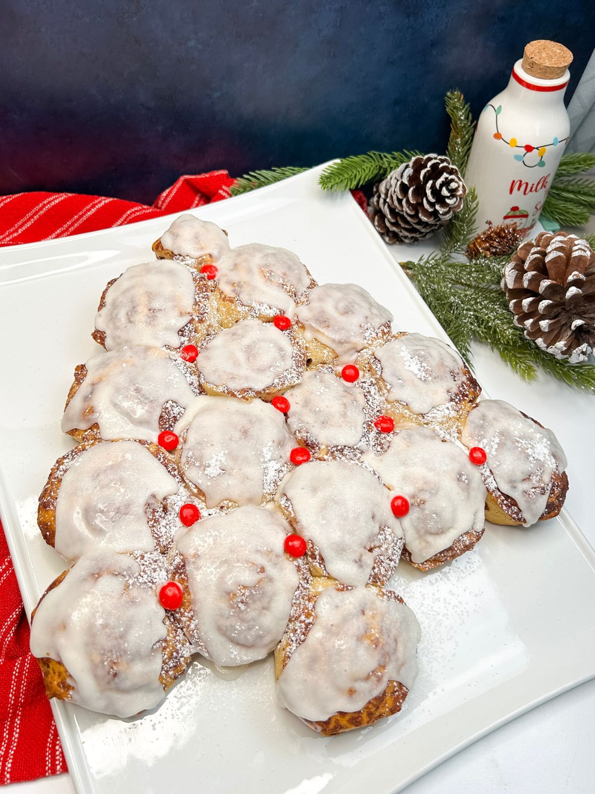 Pillsbury Cinnamon Rolls Christmas Tree with greenery, pine cones, and milk for Santa in the background.