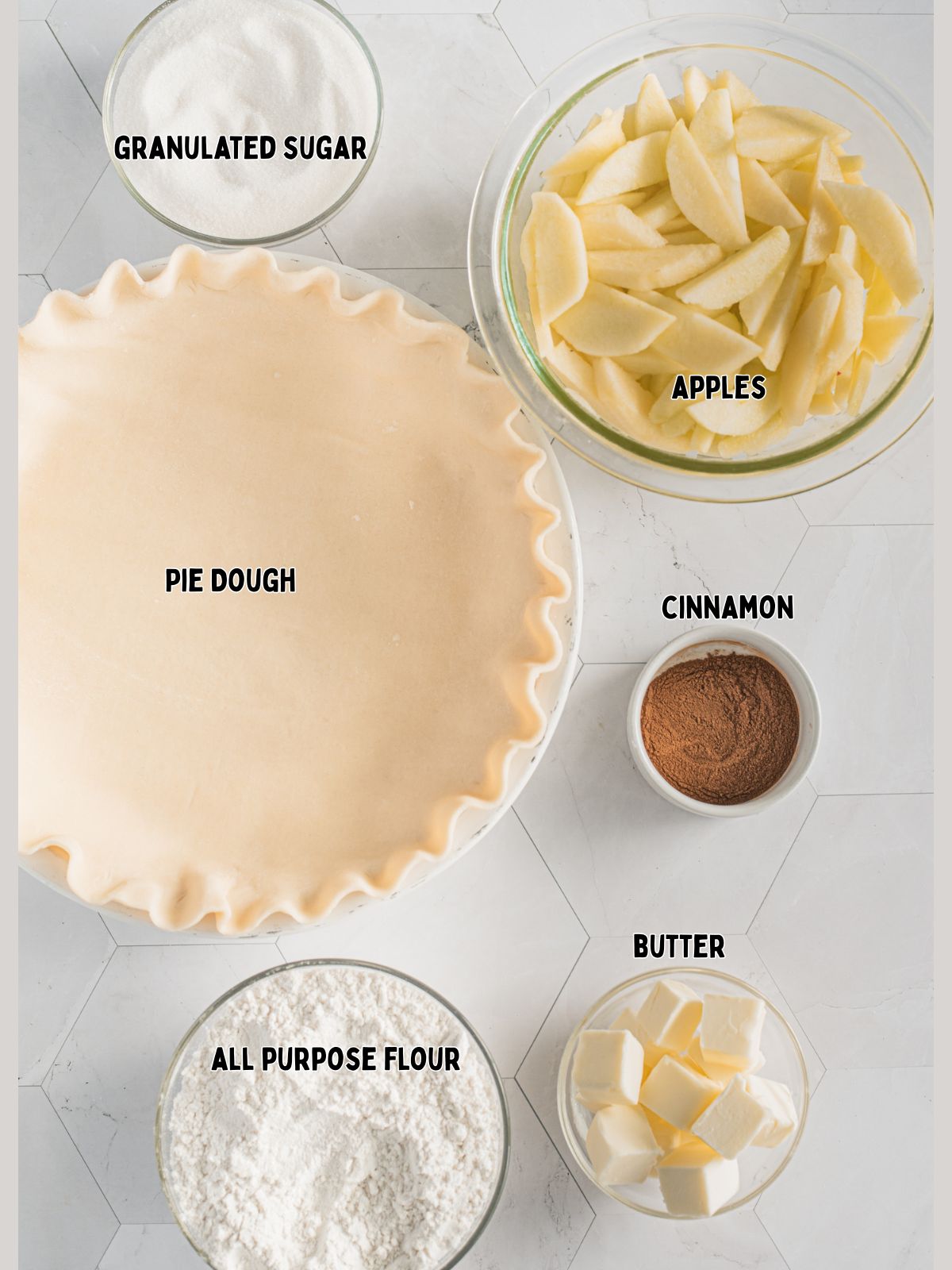 Ingredients in bowls for apple pie of flour, butter, cinnamon, sugar and a pie crust in pie plate.