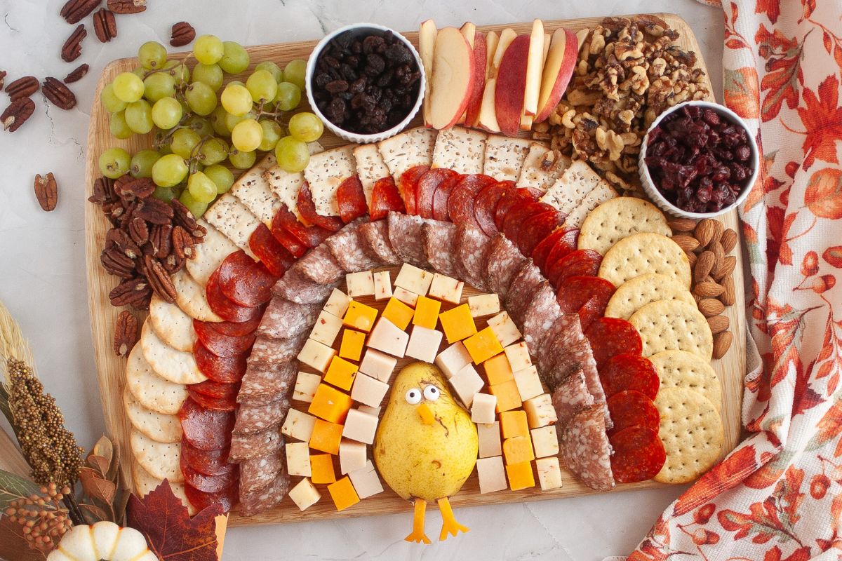 Thanksgiving Turkey Charcuterie Board filled with cheeses, meats, crackers, fruit, and nuts.