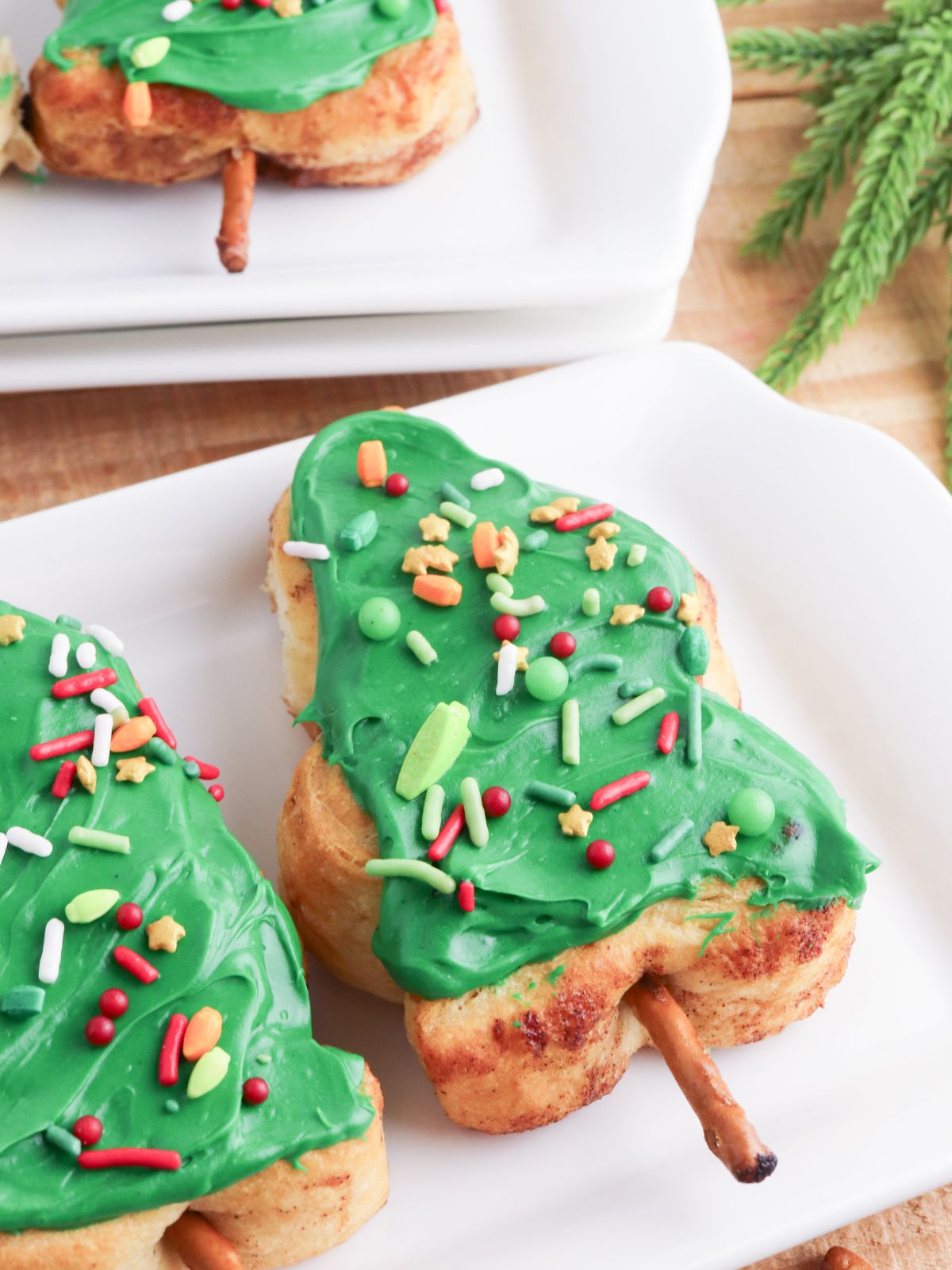 Close up of a cinnamon roll Christmas tree with green frosting and sprinkles.