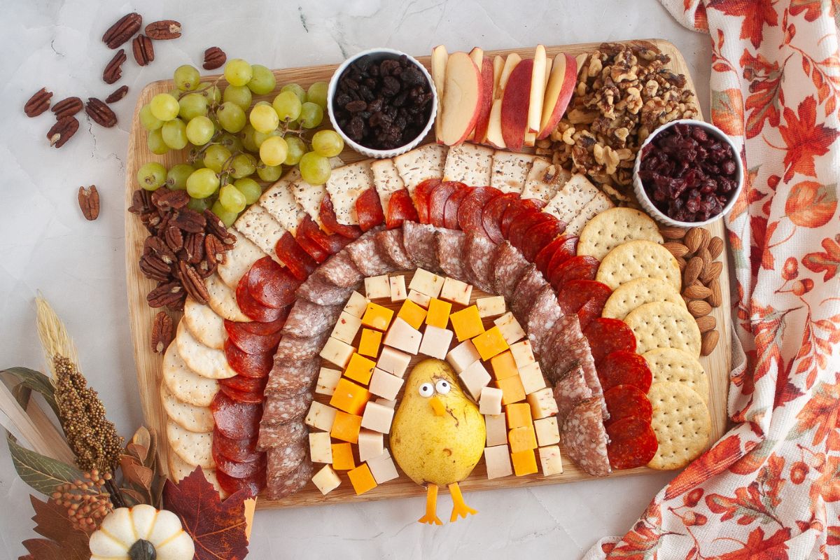 Overhead view of the charcuterie board with a turkey's tail feathers made out of cheeses, meats, and crackers.