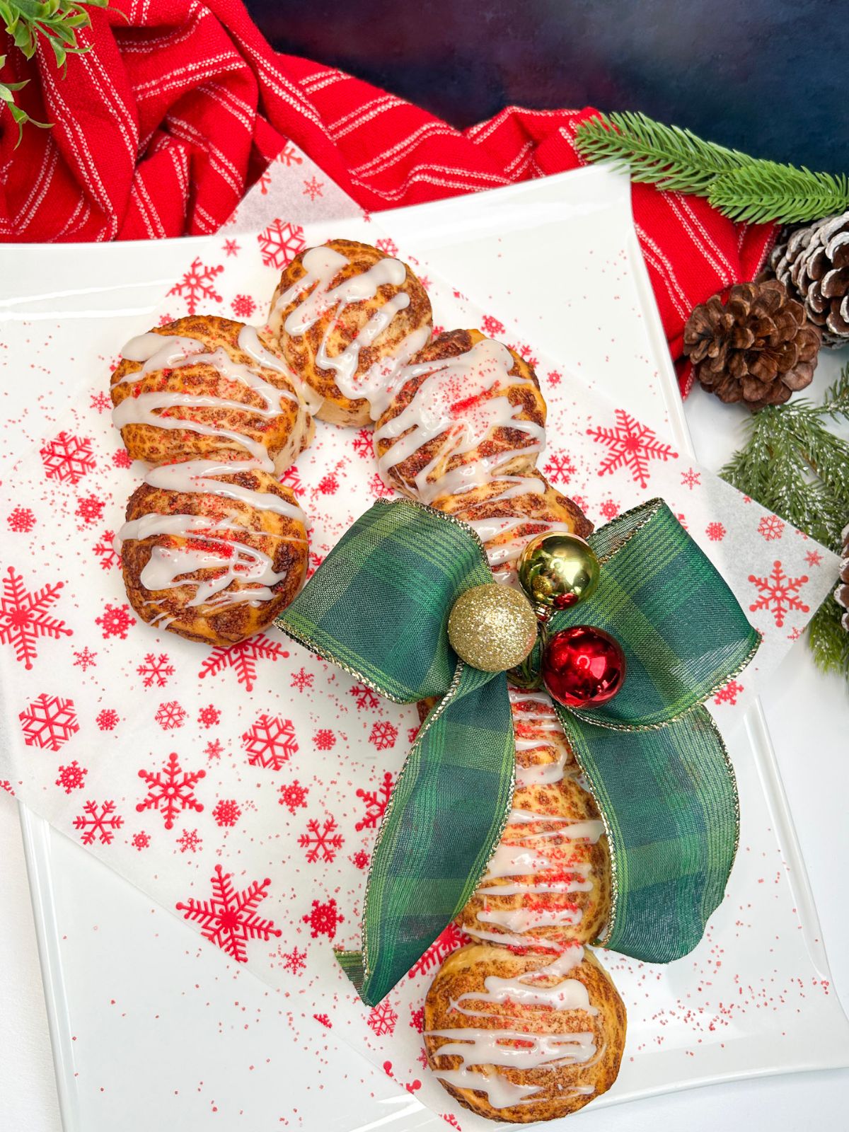 candy cane made from refrigerated cinnamon rolls with green fabric bow on white platter.