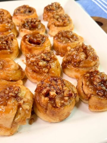 mini pecan rolls on white platter.