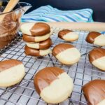 sliced shortbread cookies dipped in melted chocolate on cooling rack.
