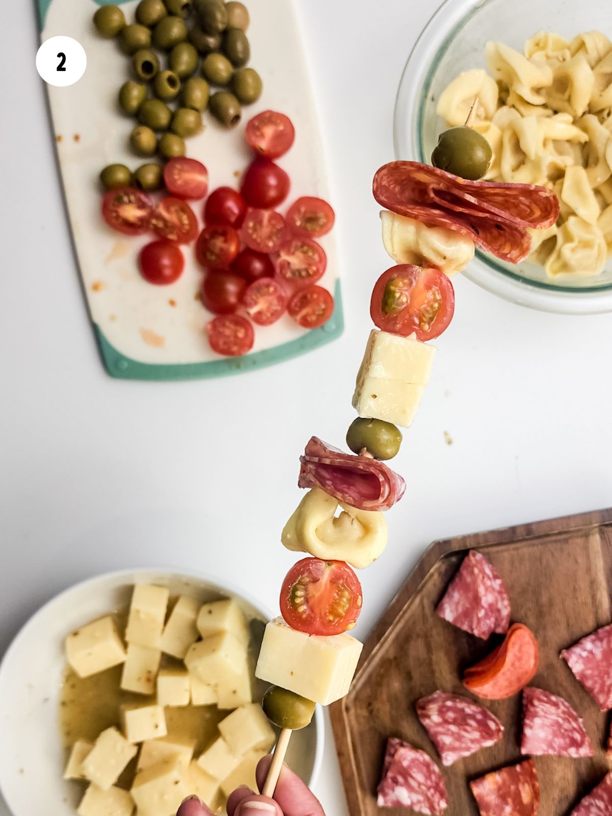 Skewer assembled with cheese, tomatoes, olives, pasta, and meats.